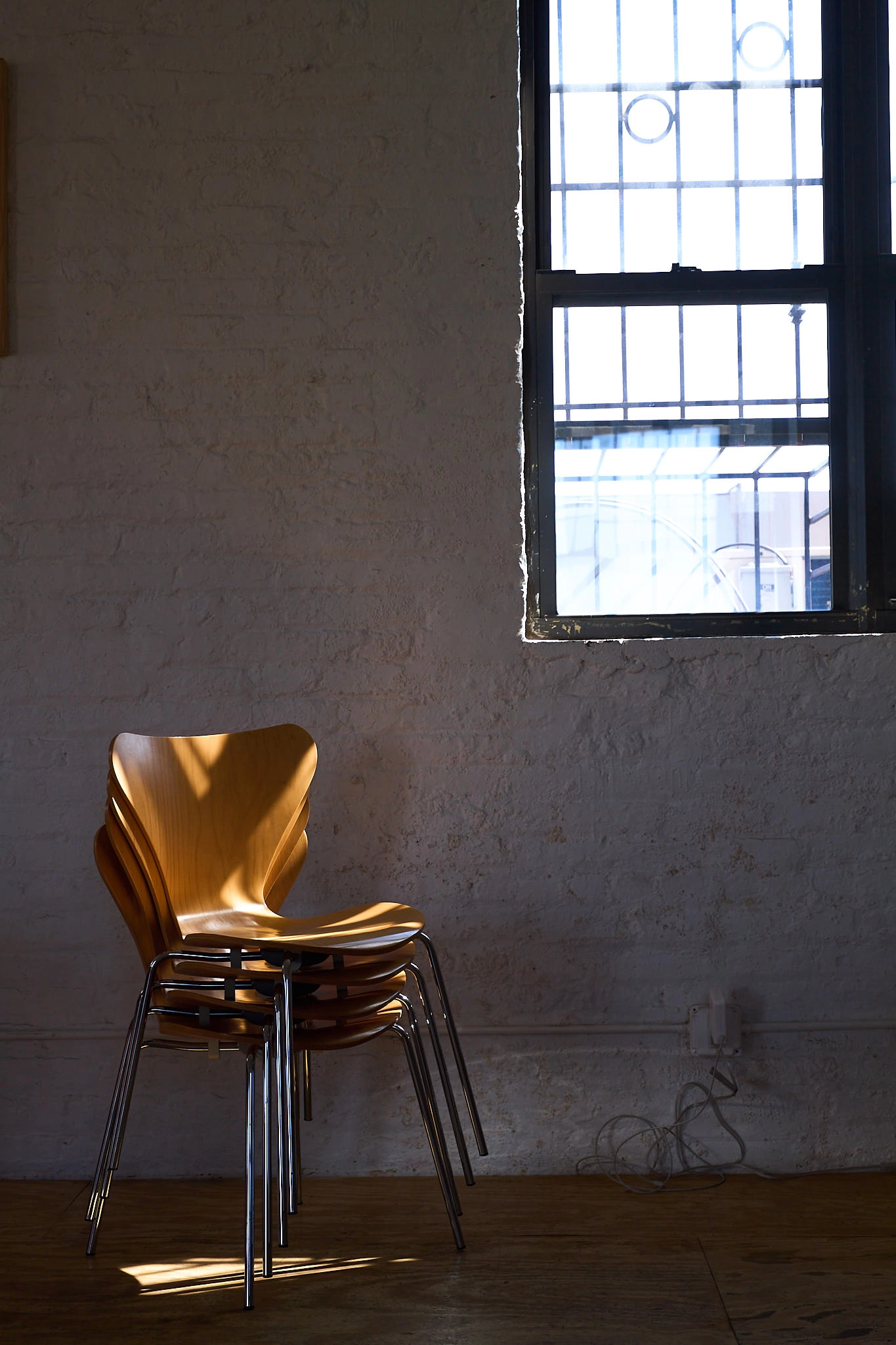 Dappled light hitting a stack of four wooden chairs.