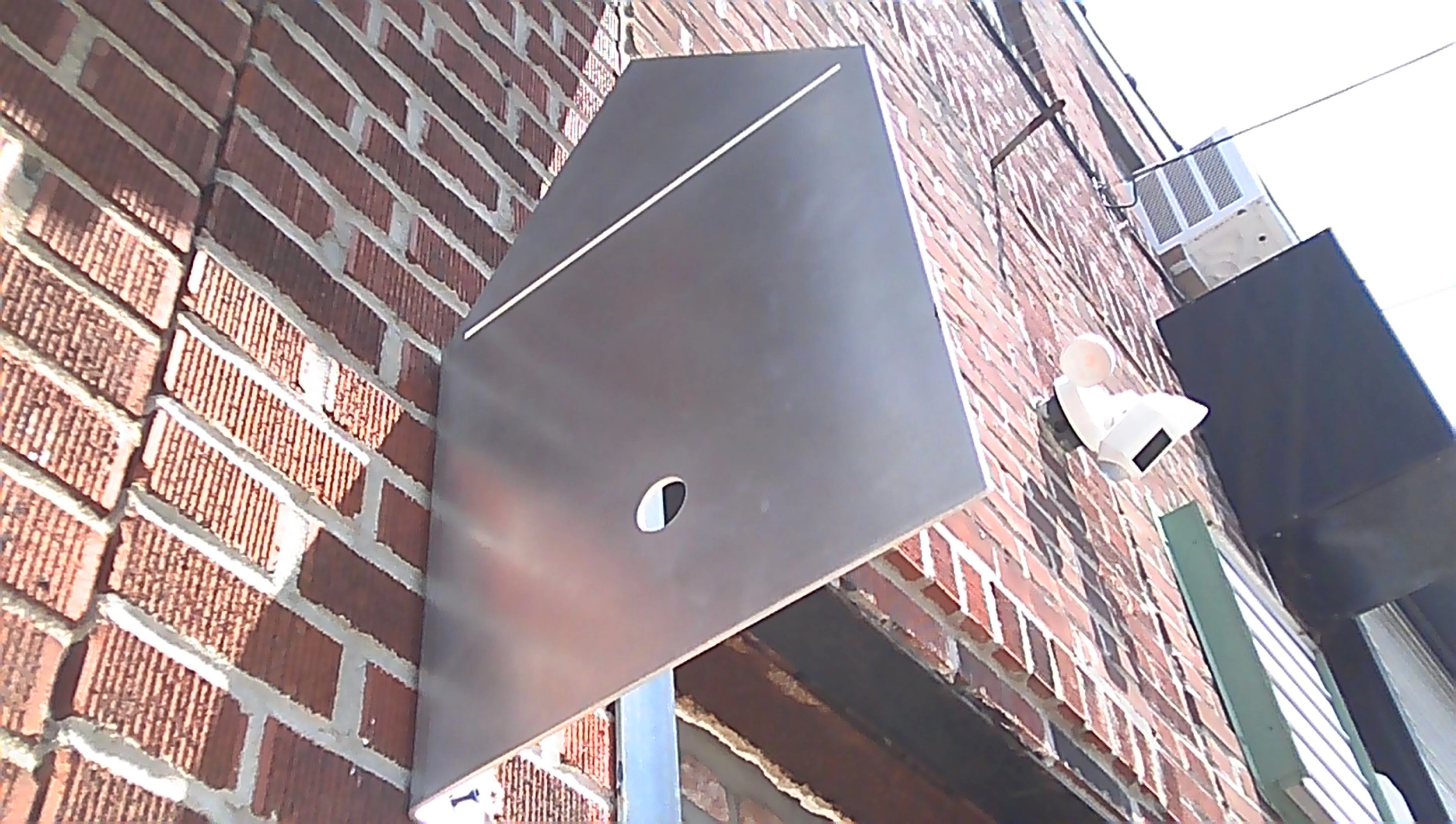 A wide-angle photo of the sunny telos.haus kitchen, including a large white island. In the background, a stage. The plywood floors gleam in the light, and various supplies and cookware are visible in the island shelves.